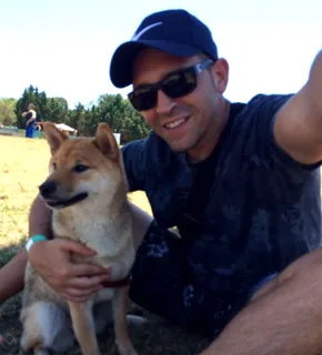 David Sánchez con Akira, su Shiba Inu, sentados en la hierba en un día de sol